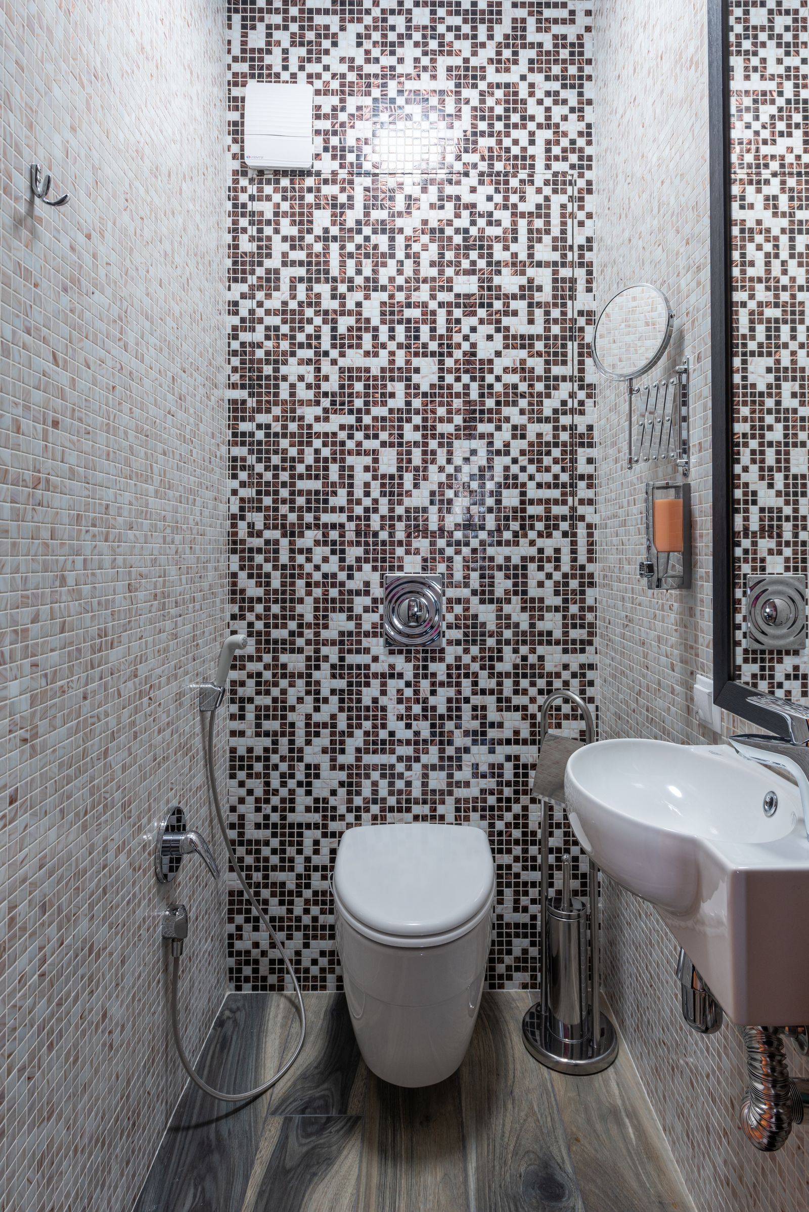 White toilet and compact sink in a tiled bathroom